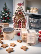 Load image into Gallery viewer, Gingerbread house, star-shaped cookies, and Christmas-themed candles on a kitchen counter.
